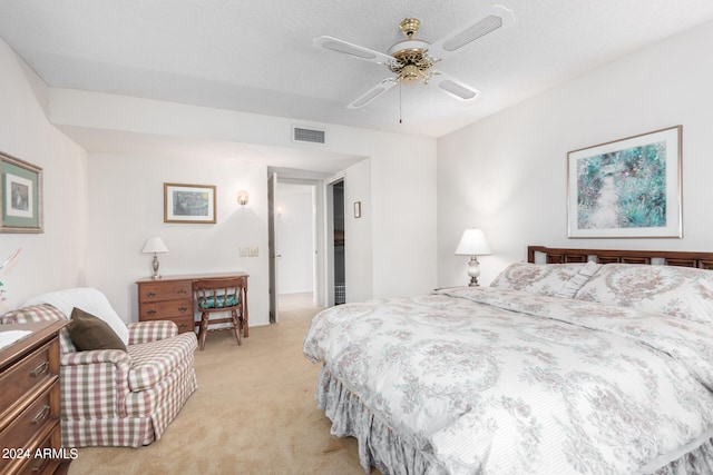 bedroom featuring light colored carpet, ceiling fan, and a textured ceiling