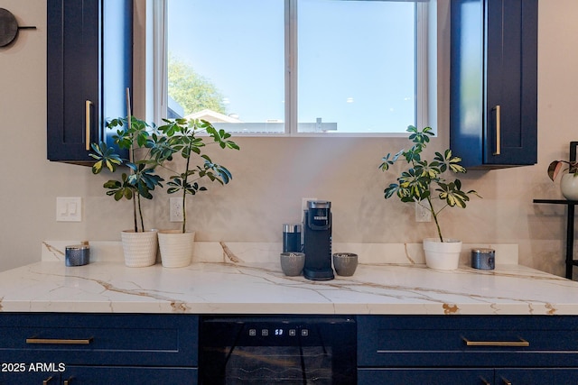 kitchen featuring beverage cooler, blue cabinets, and light stone countertops