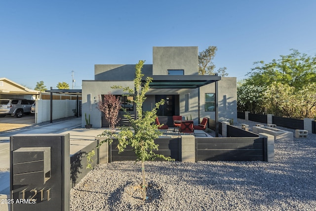 modern home with outdoor lounge area, stucco siding, fence, and a patio
