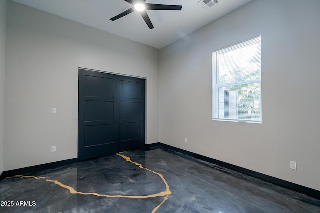 unfurnished bedroom with finished concrete flooring, baseboards, a closet, and a ceiling fan