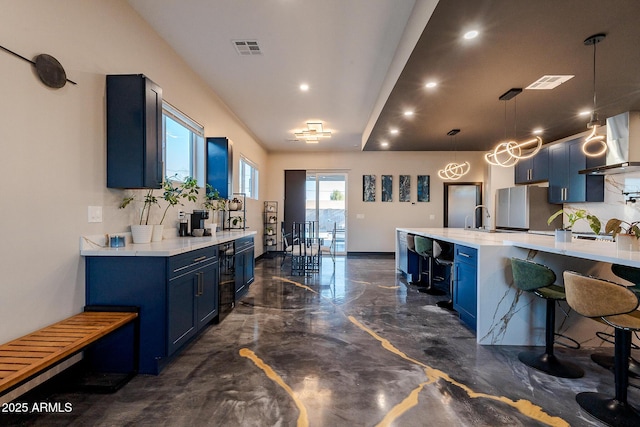 kitchen featuring blue cabinets, freestanding refrigerator, backsplash, recessed lighting, and wall chimney exhaust hood