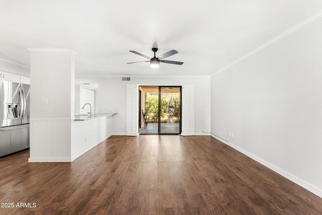 unfurnished living room with ceiling fan, visible vents, dark wood-style floors, and ornamental molding