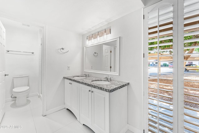 bathroom featuring tile patterned floors, toilet, baseboards, and a sink