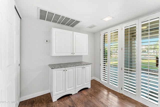 interior space with visible vents, plenty of natural light, dark wood-type flooring, and baseboards