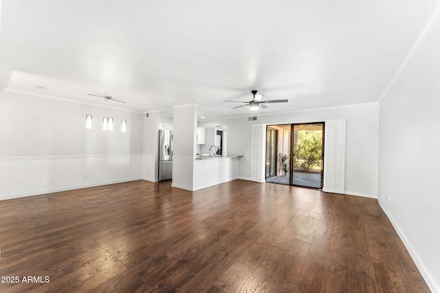 unfurnished living room with dark wood finished floors, ornamental molding, and a sink