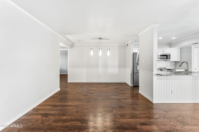 unfurnished living room with dark wood-type flooring, a wainscoted wall, and a sink