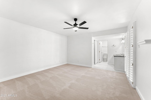 unfurnished room with a ceiling fan, light colored carpet, and baseboards