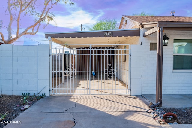 gate at dusk featuring a carport