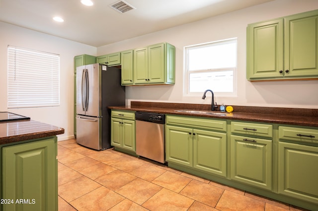 kitchen featuring sink, light tile patterned floors, stainless steel appliances, and green cabinetry