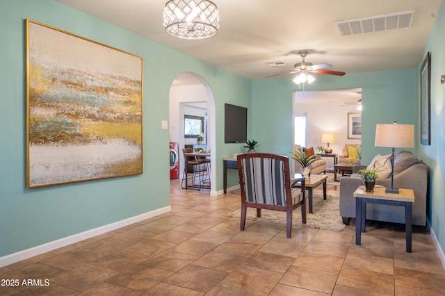 sitting room with ceiling fan with notable chandelier