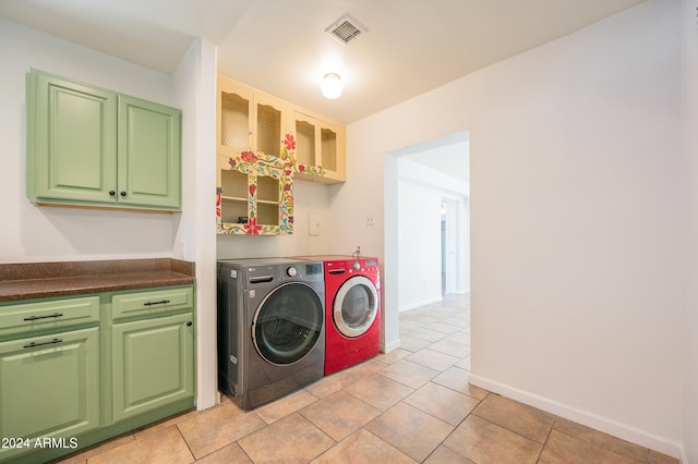 washroom with light tile patterned flooring, washing machine and clothes dryer, and cabinets