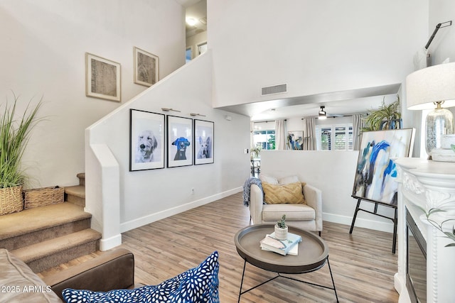 living area with light wood finished floors, visible vents, stairs, and a towering ceiling