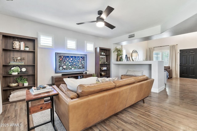 living area with ceiling fan, visible vents, and wood finished floors