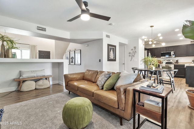 living area with light wood-type flooring, visible vents, and baseboards