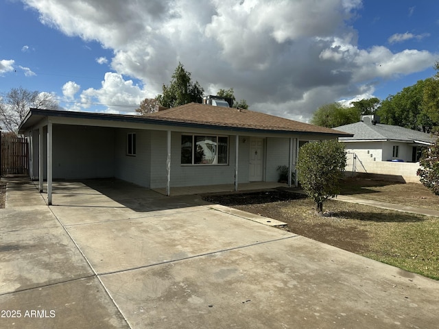 ranch-style house with a shingled roof, fence, covered porch, a carport, and driveway