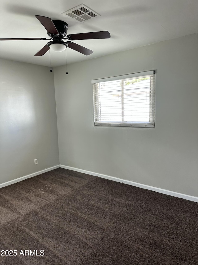 unfurnished room featuring visible vents, dark carpet, a ceiling fan, and baseboards