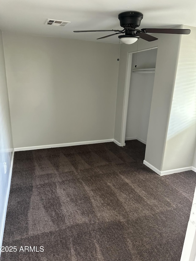 unfurnished bedroom with visible vents, dark carpet, baseboards, and ceiling fan