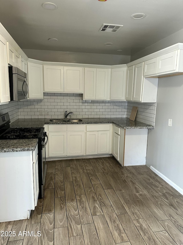 kitchen with black gas stove, stainless steel microwave, dark wood-style floors, and visible vents