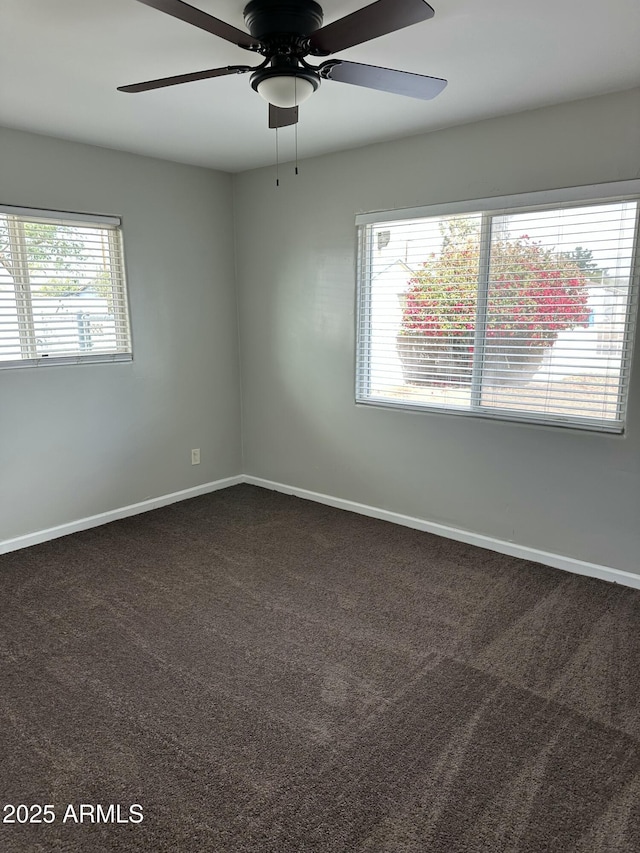 unfurnished room with baseboards, a ceiling fan, and dark carpet