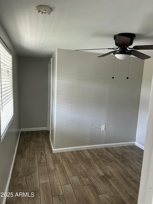 spare room featuring baseboards, wood finished floors, and a ceiling fan