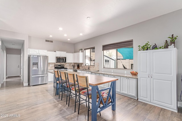 557 S Lemon Ct, Gilbert, AZ 85296 - kitchen featuring stainless steel appliances, white cabinetry, light wood finished floors, backsplash, and recessed lighting