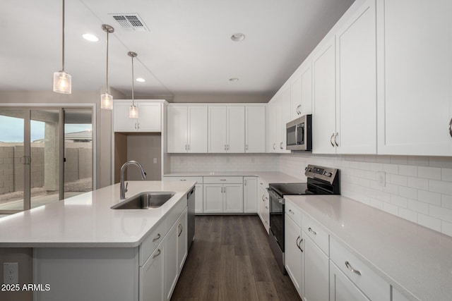 kitchen featuring visible vents, backsplash, dark wood-type flooring, appliances with stainless steel finishes, and a sink