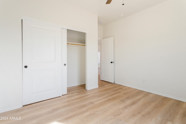 unfurnished bedroom featuring ceiling fan, a closet, and light hardwood / wood-style flooring