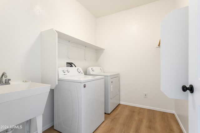 clothes washing area featuring separate washer and dryer, sink, and light hardwood / wood-style flooring