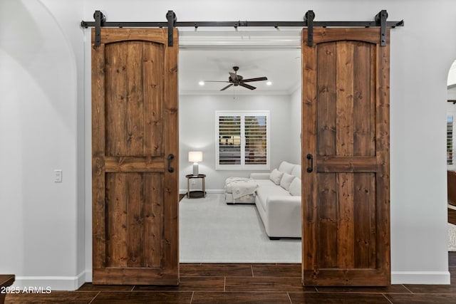 unfurnished living room featuring ceiling fan, crown molding, and a barn door