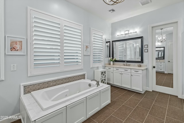 bathroom with a tub, a chandelier, tile patterned floors, and vanity