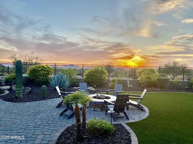 patio terrace at dusk featuring an outdoor fire pit and a yard