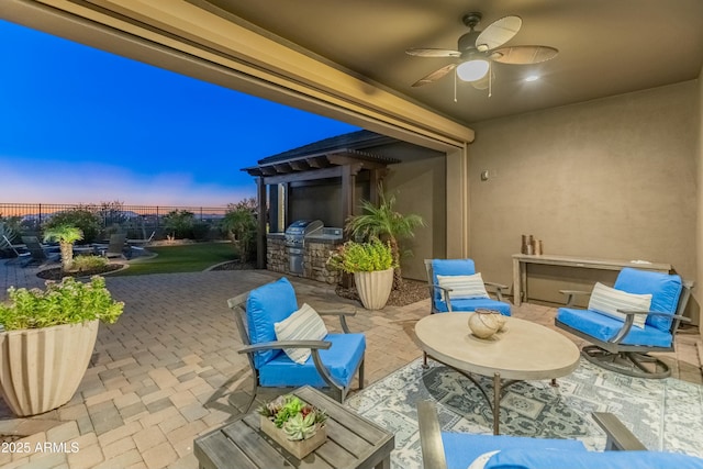 patio terrace at dusk featuring exterior kitchen and ceiling fan