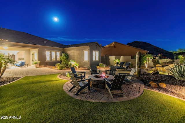 patio at twilight featuring a yard and a fire pit