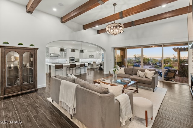 living room featuring sink, a chandelier, and beamed ceiling