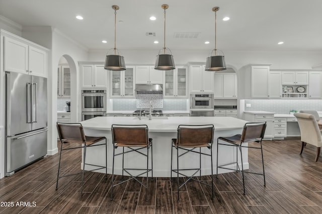 kitchen featuring white cabinets, hanging light fixtures, a center island with sink, and appliances with stainless steel finishes