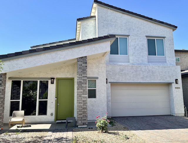 back of house featuring stucco siding, a garage, and decorative driveway