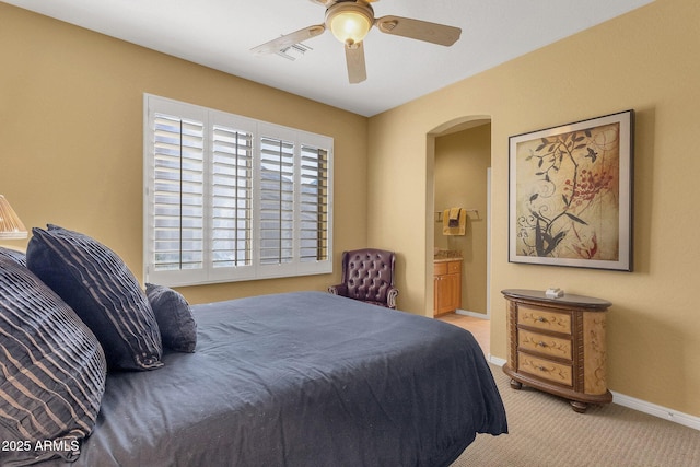 13827 N Mesquite Ln, Fountain Hills, AZ 85268 - carpeted bedroom with ensuite bathroom, baseboards, visible vents, arched walkways, and ceiling fan