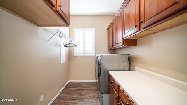 clothes washing area featuring washing machine and clothes dryer, dark wood-type flooring, and cabinets