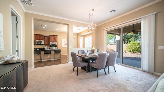 dining room with light colored carpet, an inviting chandelier, and ornamental molding