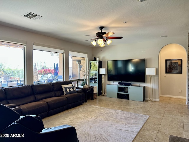living area featuring baseboards, visible vents, a textured ceiling, and ceiling fan