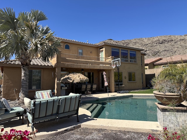 back of house featuring outdoor lounge area, a patio area, an outdoor pool, and stucco siding