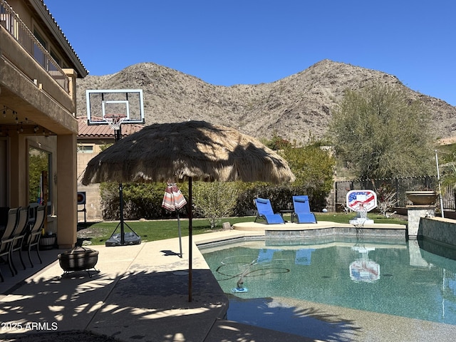 view of pool featuring a patio area, a fenced in pool, fence, and a mountain view