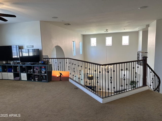 hallway with carpet flooring, an upstairs landing, and visible vents