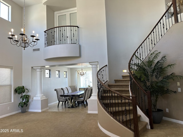 entryway featuring an inviting chandelier, stairway, decorative columns, and visible vents