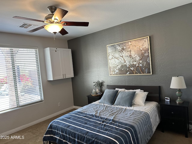 carpeted bedroom with a ceiling fan, baseboards, visible vents, and a textured wall