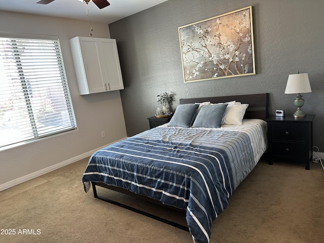 bedroom with a ceiling fan, a textured wall, baseboards, and light carpet