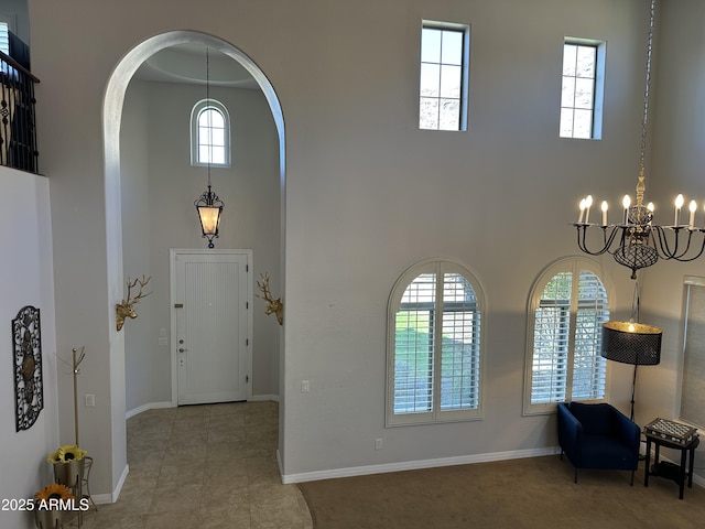 foyer featuring a notable chandelier, arched walkways, a high ceiling, and baseboards