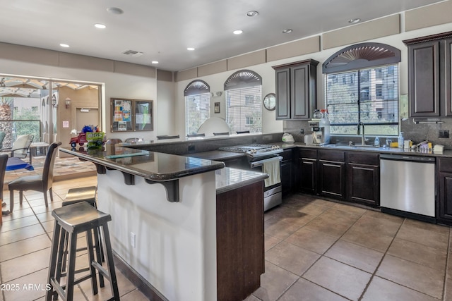 5450 E Deer Valley Dr Unit 1004, Phoenix, AZ 85054 - kitchen with appliances with stainless steel finishes, a breakfast bar area, tile patterned floors, a sink, and plenty of natural light