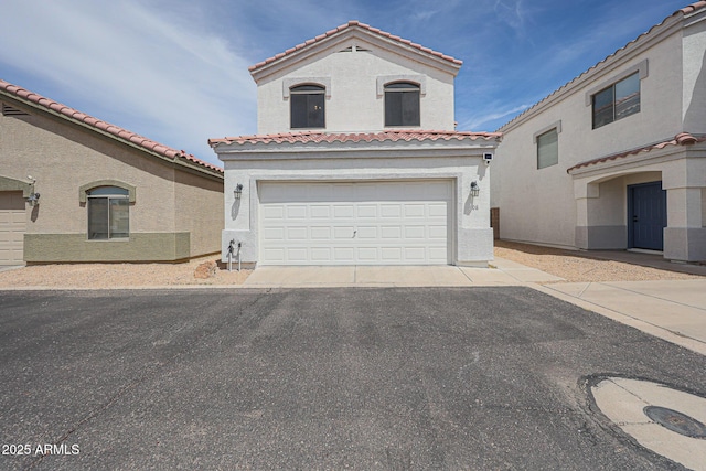 mediterranean / spanish-style house featuring a tiled roof, central AC unit, aphalt driveway, an attached garage, and stucco siding
