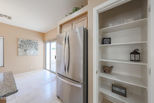 kitchen with visible vents, light brown cabinetry, baseboards, freestanding refrigerator, and light tile patterned flooring